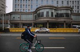 Un ciclista pasa frente a The Jade Boutique Hotel, donde los miembros del equipo de la Organización Mundial de la Salud (OMS), que investigan los orígenes de la pandemia del coronavirus Covid-19 cumplieron su cuarentena, en Wuhan, provincia central de Hubei en China, el 28 de enero. 2021.