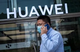 Un hombre pasa hablando por teléfono celular junto a una tienda de Huawei en Pekín, China.
