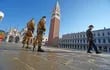 Dos soldados patrullando y un peatón con mascarilla son vistos en la plaza San Marco, en Venecia, Italia.