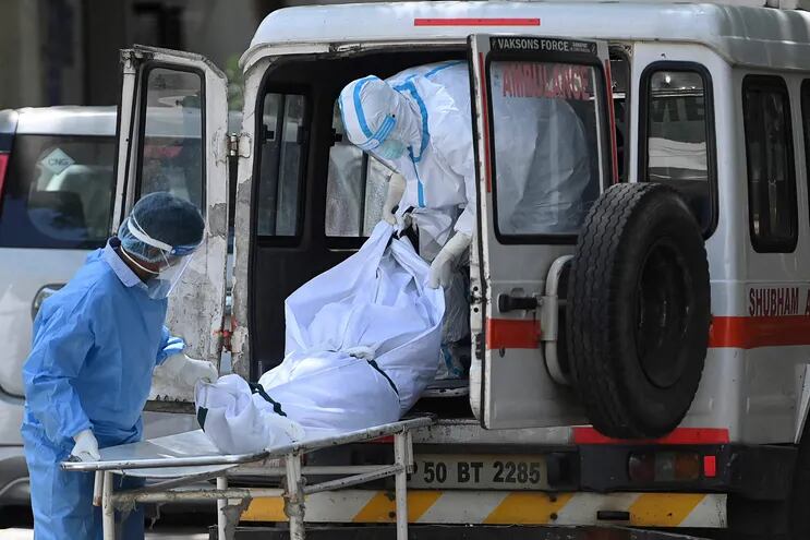 Trabajadores médicos bajan un cuerpo de una ambulancia, en una funeraria en Nueva Delhi, India.