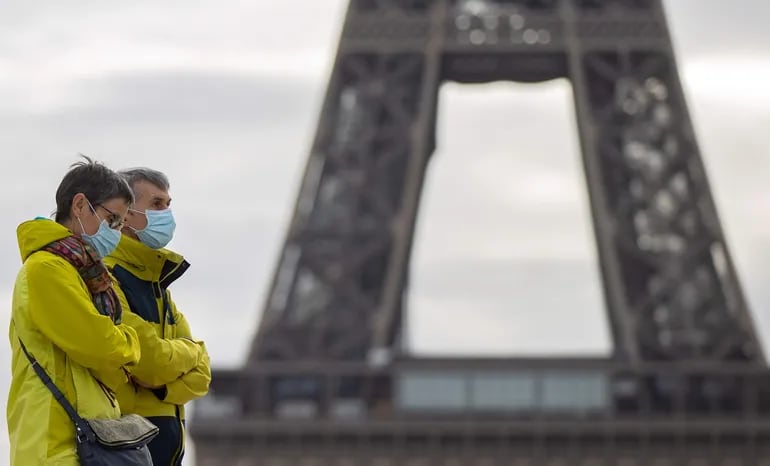 Peatones llevan máscaras protectoras al pasar frente a la Torre Eiffel en París.