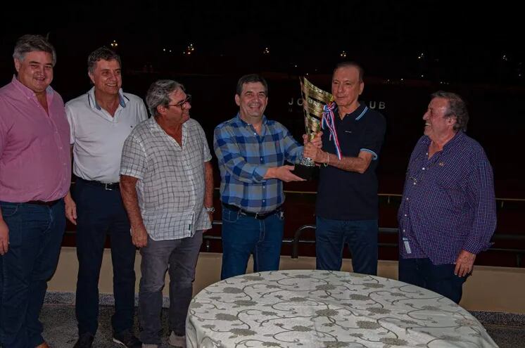 Hugo Velázquez (i), dueño de Palo Santo, recibe el trofeo de Juan Carlos Aveiro, titular del Jockey.