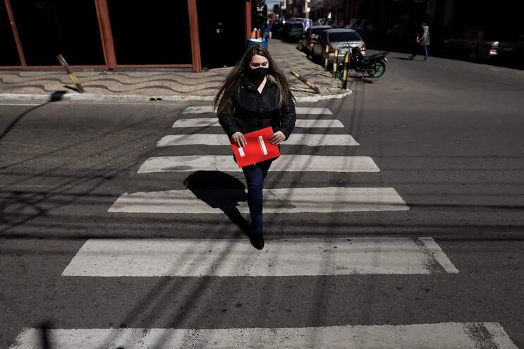 Una mujer con tapabocas cruza una calle en el centro de Asunción.