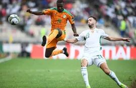 El marfileño Nicolás Pepe puntea el balón anticipándose al defensor argelino Ramy Bensebaini