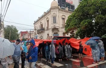 Miembros de la multisectorial se manifiestan frente el Ministerio de Urbanismo bajo la lluvia.