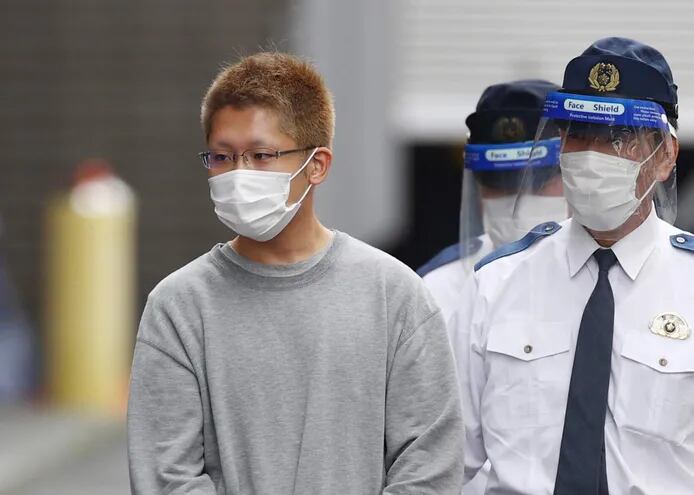 Kyota Hattori (izq.), sospechoso de 24 años de un ataque con cuchillo e incendio provocado en un tren de Tokio, es llevado ante la fiscalía bajo sospecha de intento de asesinato.
