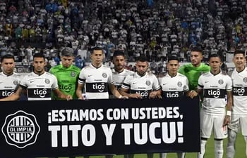 Los jugadores de Olimpia con el cartel de apoyo a Iván Torres y Víctor Salazar, quienes fueron víctimas del atentado de San Bernardino durante el Ja'umina Fest.