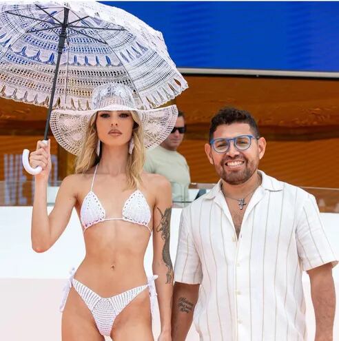 El compatriota Dany Bogado junto a una modelo que lleva un sombrero y una sombrilla, ambos de ñandutí.