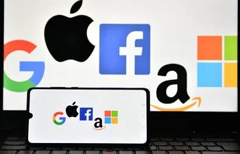 Logos de Google, Apple, Facebook, Amazon y Microsoft en la pantalla de un celular y una laptop.