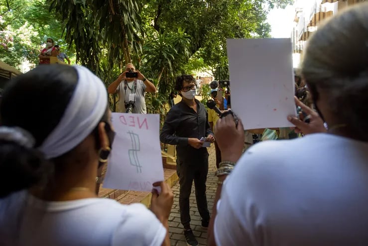 El opositor cubano Yunior García (c) habla con mujeres (de espaldas) que se manifestaron con carteles en su contra, tras salir del edificio de la intendencia del municipio Habana Vieja, donde le fue denegado el permiso para llevar a cabo una marcha pacífica el próximo 15 de noviembre.