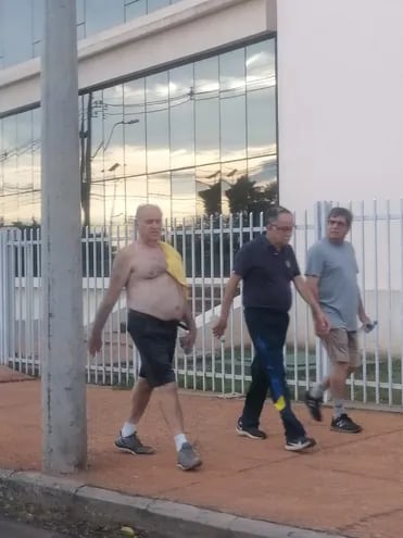 Ramón González Daher, sin remera, junto a su amigo Darío Cáceres, actual vicepresidente del club Sportivo Luqueño y otra persona caminando tranquilamente alrededor de la Confederación Sudamericana de Fútbol en Luque, el domingo a la tarde, luego de haber sido condenado a 15 años de prisión.