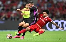 El colombiano Luis Díaz (d), del Liverpool, se tira a los pies del alemán Arijon Ibrahimovic, del Bayern Munich, durante el partido amistoso disputado ayer en Singapur.