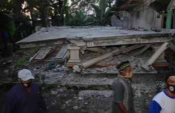 Los pobladores pasan frente a una casa derrumbada en la aldea de Sidorenggo, en Malang, Java Oriental, después de que un terremoto de magnitud 6,0 ​​sacudiera la costa de la isla de Java en Indonesia.