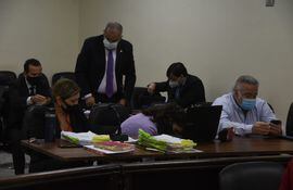 El exsenador Óscar González Daher revisa su teléfono celular mientras Jorge Oviedo Matto busca un sitio para sentarse durante el juicio en la jornada de hoy.