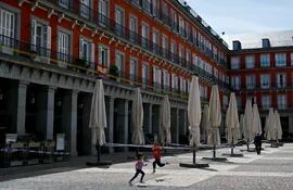 Dos niños juegan al lado de la terraza cerrada de un bar en la Plaza Mayor de Madrid.