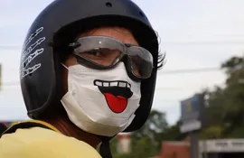 Con humor es mejor. Un motociclista sobre la ruta Transchaco, en Mariano Roque Alonso, usa un barbijo con el diseño de una boca sacando la lengua.