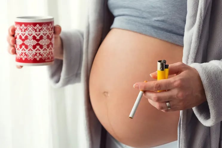 Mujer embarazada fumando y tomando café