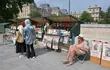 Un librero de 65 años sentado en su puesto, vendiendo libros antiguos y carteles antiguos, en la orilla izquierda del río Sena en París.