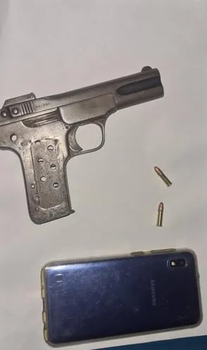 Arma de fuego con la que asaltó el adolescente y el teléfono recuperado.