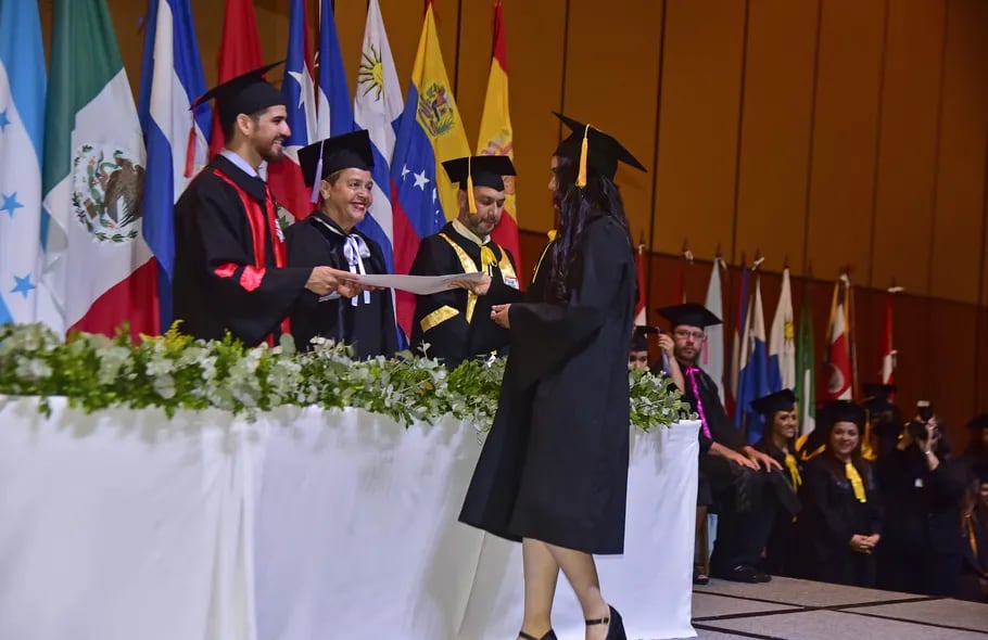 El director académico de la Facultad de Postgrados de la UNIBE, Eduardo Velázquez Romero, entregando uno de los títulos.