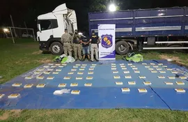 Agentes policiales de Antinarcóticos custodian la cocaína encontrada dentro del tractocamión y también al chofer arrestado, identificado como Juan Andrés Ortega Cáceres.