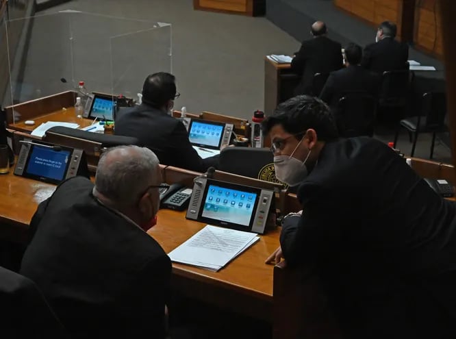 El diputado Nazario Rojas (ANR, HC), de espaldas y el diputado Raúl Latorre (ANR, HC) conversan en la sala de sesiones.