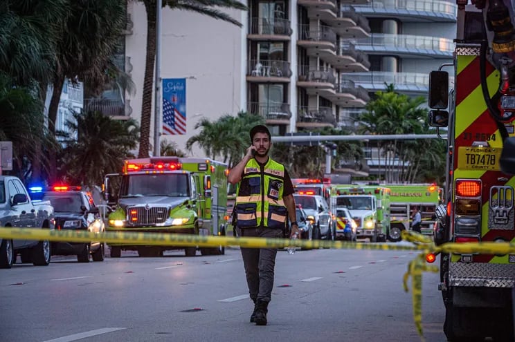 Un miembro de primeros auxilios camina frente a varios camiones de bomberos cerca del edificio de 12 pisos parcialmente colapsado hoy, cerca de 88th Street y Collins Avenue, en la ciudad de Surfside, al norte de Miami Beach, Florida (EE.UU.).