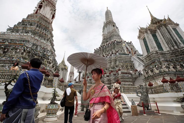 Turistas chinos vestidos con tradicionales trajes tailandeses posan en el templo Wat Arun en Bangkok, Tailandia.