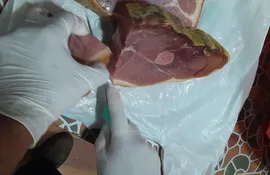 Un funcionario de Senacsa corta los pedazos de carne porcina que fueron traídos desde España por una pareja de paraguayos y fue confiscada.
