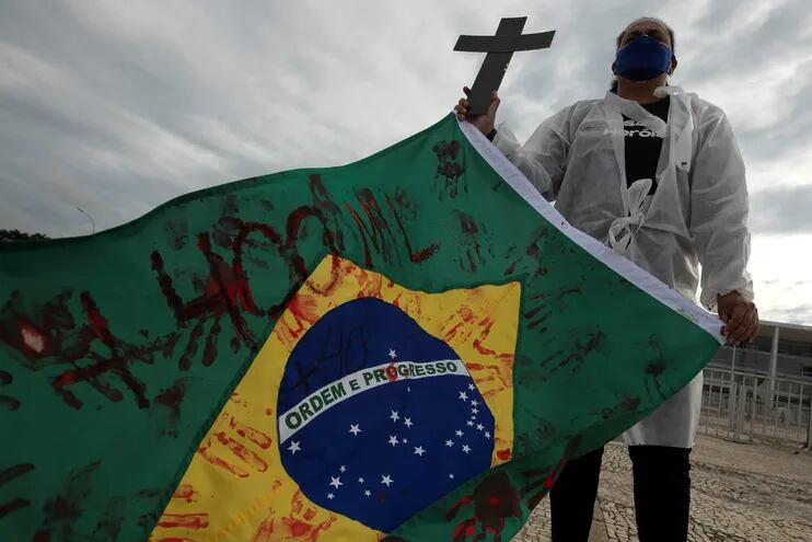 Una enfermera sostiene una bandera de Brasil en una protesta simbólica en honor a los profesionales de la salud y por las más de 400.000 muertes por coronavirus en Brasil hoy, frente al Palacio do Planalto en Brasilia (Brasil).