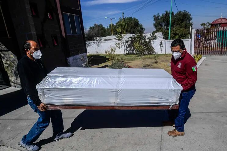 Workers carry an empty coffin at the Municipal Pantheon of Ecatepec, Mexico state, Mexico, on February 2, 2021, amid the new coronavirus pandemic. (Photo by PEDRO PARDO / AFP)