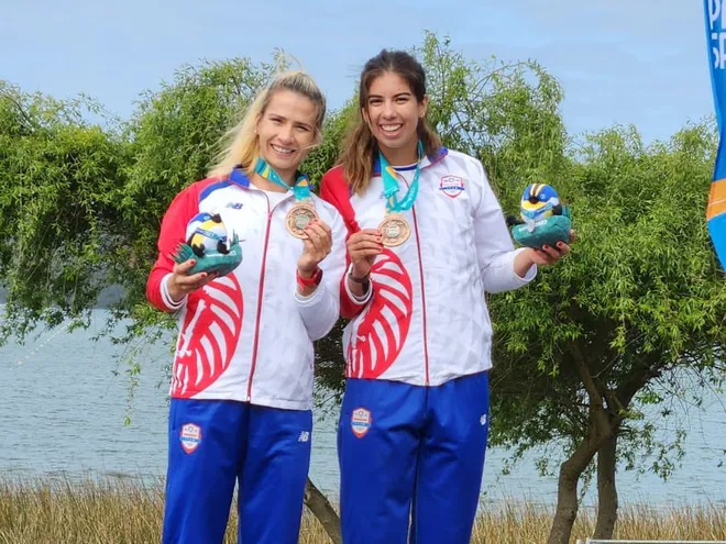 Las paraguayas Alejandra Alonso (i) y Nicole Martínez celebran la conquista de la medalla de bronce en la premiación del Remo en los Juegos Panamericanos Santiago 2023.