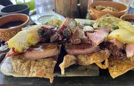 ACOMPAÑA CRÓNICA: MÉXICO GASTRONOMÍA***MEX9470. VALLADOLID (MÉXICO), 25/07/2022.- Vista de un platillo preparado con carne ahumada, longaniza y poc chuc servido sobre una tabla el 23 de julio de 2022 en el restaurante Achiote, poblado de Tikuch, Valladolid, estado de Yucatán (México). En la pequeña comunidad de Kaua, en el estado mexicano de Yucatán, 10 restaurantes tradicionales cocinan el poc chuc, un guiso prehispánico a base de carne de puerco, que identifica al lugar al que los guías y visitantes han llamado "La ruta de las tías", parte del camino gastronómico a las ruinas mexicanas de Chichen Itzá. EFE/Lourdes Cruz
