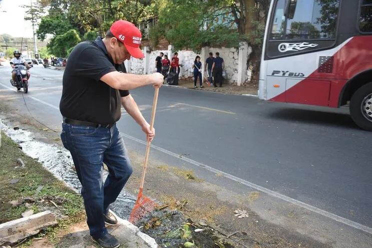 En la fotografía se ve a un hombre, el intendente de Lambaré, Guido González, utilizando un rastrillo en la calle.