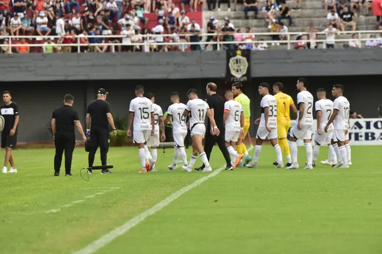 Los jugadores de Olimpia, con Aitor García, entrenador interino, en el centro, abandonan el campo de juego del Antonio Aranda después de finalizar el primer tiempo contra General Caballero JLM por la séptima fecha del torneo Apertura 2023 del fútbol paraguayo.