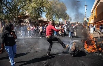 Un hombre patea un mueble quemado durante los disturbios en el suburbio de Turffontein, en Johannesburgo, el lunes.