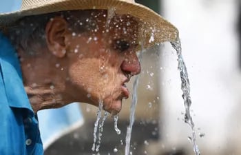 Un hombre se refresca en una fuente para aliviar las altas temperaturas.
