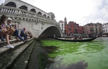 La gente observa una mancha de color verde fosforescenteen el Gran Canal cerca del Puente de Rialto, en Venecia, este domingo. Los bomberos tomaron muestras de agua, mientras que el Prefecto de Venecia convocó una reunión urgente entre las fuerzas policiales de la ciudad, ya que aún se desconoce la causa.