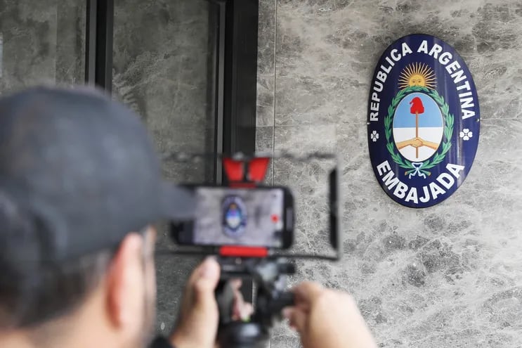 Un hombre graba el escudo de la República de Argentina en la entrada de la embajada de Argentina, en Bogotá (Colombia).