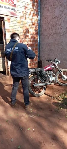 Un agente de Investigaciones de Caaguazú, verifica la motocicleta utilizada por el sospechoso para escapar de la escena del alevoso crimen.