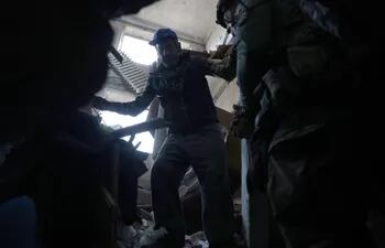 Un policía militar ucraniano evacúa a civiles de un edificio dañado por un bombardeo ruso cerca de Avdivka, el pasado 15 de abril.