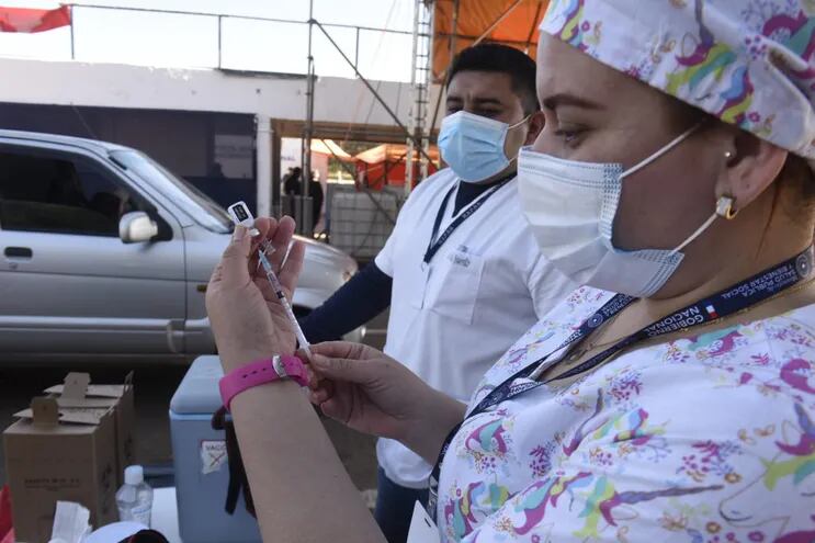 Una funcionaria de blanco prepara una de las dosis de la vacuna de Pfizer en el autódromo Rubén Dumot, exAratirí.