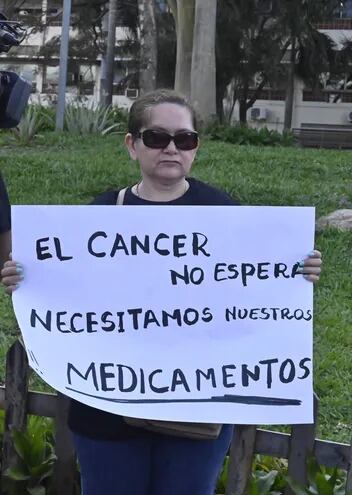 Una asegurada del IPS sostiene un cartel en reclamo a la falta crónica de medicamentos oncológicos.