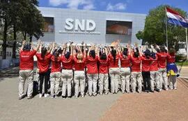 Voluntarios en la Secretaría Nacional de Deportes en torno a la antorcha de los Juegos Suramericanos.