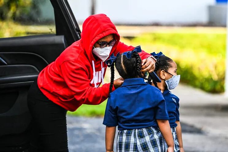 Una mujer ajusta la mascarilla de una niña en la entrada de un colegio en Miami, Florida.