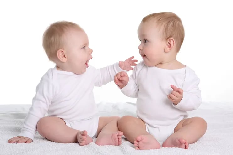 Dos bebés vestidos con ositos blancos hablan entre sí