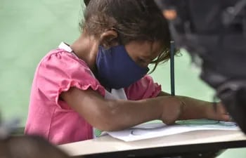 Sin posibilidad de dar clases presenciales, una niña recibe refuerzo escolar en una improvisada escuelita del Bañado Norte, atendida por voluntarios.