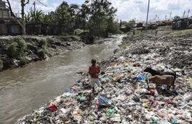 Nairobi (Kenya).- A boy scavenges on a dumpsite next to a river bank as plastic bottles are captured by one of the machines innovated by Kenyan start-up company Chemolex in Kariadudu, Nairobi, Kenya, 21 November 2022 (issued 24 November 2022). Chemolex has installed 10 plastic capture devices designed to automatically remove plastic and other wastes flowing along the Athi River and its major tributaries as part of global efforts to keep oceans clean and to protect the health of the residents. Recycling infrastructures then turn plastic wastes trapped and removed from the river sections into construction industry products, including pavement blocks for walk paths, cycle way, fencing poles and construction bricks. To date, the company's devices have removed over 590,000 kg of plastic waste. Chemolex aims at developing 200 innovative plastic capture devices by the end of 2025, in order to remove plastic and other wastes flowing along Africa's major rivers. (Ciclismo, Kenia) EFE/EPA/DANIL IRUNGU
