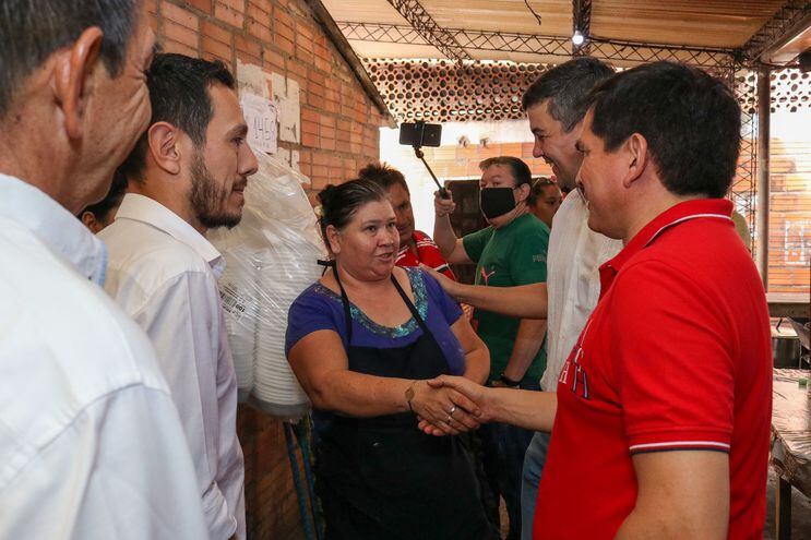 Santi Peña acompañado del Gobernador Juan Carlos Baruja, el Intendente Marcelo Simbrón, saludando a una trabajadora del mercado