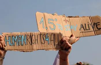 Activistas portan carteles durante una manifestación exigiendo limitar el aumento de la temperatura global.